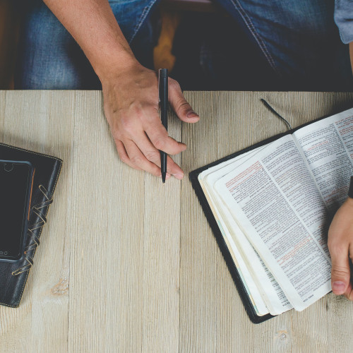 man holding a pen with a bible on the side